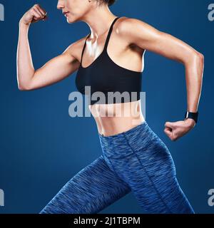 Per stare in forma, è necessario lavorare in modo più completo. Studio girato di una donna vestita irriconoscibile che si posa su uno sfondo blu. Foto Stock