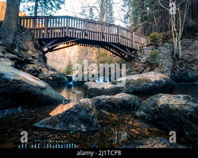 Un bel colpo di un vecchio ponte di legno su un fiume con massi a Verlobungsinsel, Okertal Harz, Germania Foto Stock
