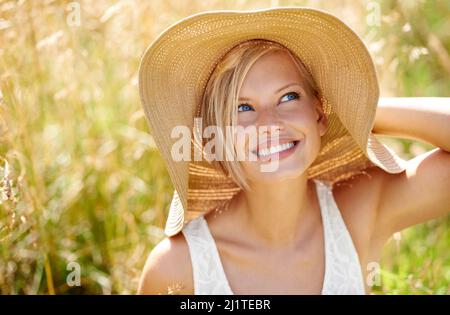 Crogiolarsi ai raggi del sole. Scatto di una bella giovane donna in un vestito che cammina attraverso la foresta. Foto Stock