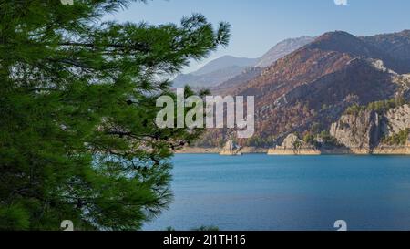 Vista dal pendio alla diga di Oymapinar attraverso rami di alberi in Turchia Foto Stock