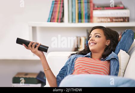 Guardando uno di quei film di tatto-buon. Scatto di una giovane donna che guarda la televisione a casa. Foto Stock