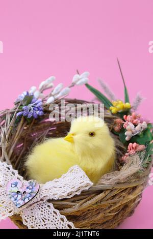 Pulcino giallo in nido su sfondo rosa. Pasqua, compleanno, giorno della madre/ spazio per la copia Foto Stock