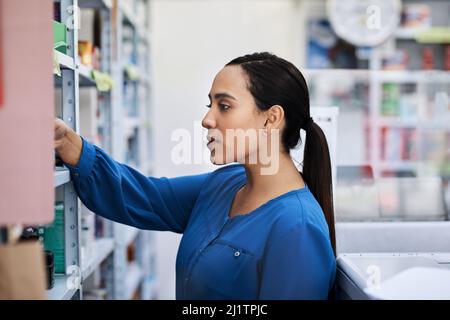 Quale è il migliore per farmi migliorare. Shot di una giovane donna che acquista in una farmacia. Foto Stock