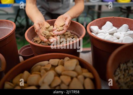 Molte pietre naturali decorative sono vendute nel mercato delle costruzioni. Materiali di costruzione. Di mani femminili sceglie pietre per decorazione. Foto Stock