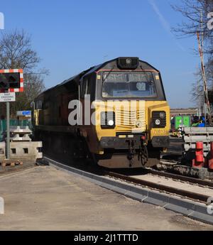 Colas Rails diesel locomotiva 70813 attraversando lentamente il livello in fase di ricostruzione Strand Road attraversando Preston con un treno di petroliere vuote. Foto Stock
