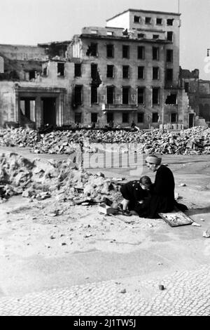 Mutter sitzt mit kind vor den Überresten der Neuen Reichskanzlei, 1946. Madre con bambino seduto sul terreno di fronte ai resti della Cancelleria del nuovo Reich, 1946. Foto Stock