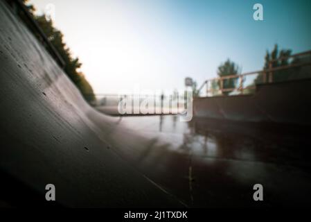 Rampa di pattinaggio o mezza pipa di pattino in una giornata buia e piovosa. Abbandonato o abbandonato pattinaggio halfpipe closeup in un paesaggio urbano apocalittico o post apocalisse Foto Stock