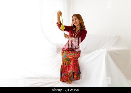 Una giovane signora malese celebra la fine del ramadan, il mese santo islamico, vestito con tradizionale abito Kebaya rosso colorato, e tenendo un cibo tradizionale Foto Stock