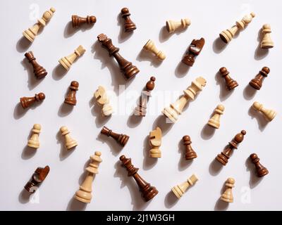 Vista dall'alto di scacchi bianchi e marroni caduti su sfondo bianco. Foto Stock
