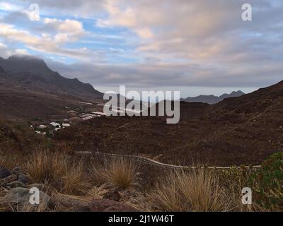 Paesaggio della costa occidentale dell'isola di Gran Canaria, Spagna con villaggio remoto la Aldea de San Nicolas circondato da aspre montagne in giornata nuvolosa. Foto Stock