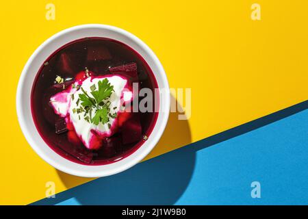 Da sopra di ciotola con gustoso borscht fatto con barbabietola su sfondo di colori della bandiera Ucraina Foto Stock