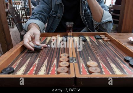Primo piano donna che tiene i dadi del backgammon e che gioca il backgammon all'esterno. Il fuoco è sulla sua mano. Foto Stock