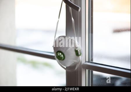 Maschera protettiva per la bocca medica per la polvere chirurgica, respiratore monouso FFP3 appeso alla finestra Foto Stock