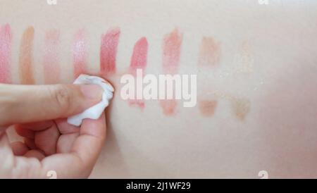 Pulire a mano i patch del rossetto disegnati su una pelle, con un tampone di cotone in pezzi. Foto Stock