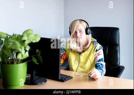 Ritratto di una donna di mezza età che indossa cuffie e guarda il webinar sul computer dell'ufficio Foto Stock