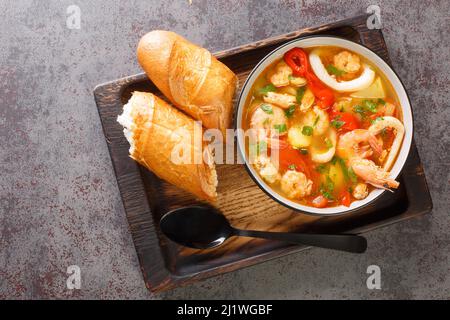 Stufato di pesce mediterraneo con patate, peperoni, pomodori e cipolle da vicino in una ciotola sul tavolo. Vista dall'alto orizzontale dall'alto Foto Stock