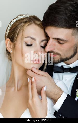 Un elegante bridegroom cute abbraccia una sposa in un abito da sposa. Gli sposi novelli abbracciano la stanza e trascorrono del tempo insieme Foto Stock