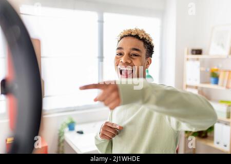 Uomo multirazziale blogger gesturing mentre registra e filma il suo vlog a casa Foto Stock