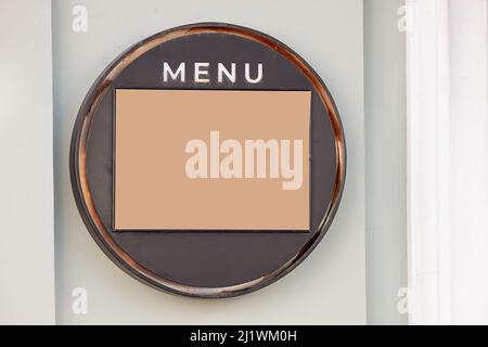 Ristorante con cartello design mockup. Vuoto per il menu in una cornice rotonda in metallo su una parete di cemento chiaro Foto Stock