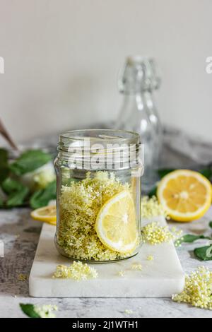 Sciroppo di elderflower fatto in casa con fiori di sambuco appena raccolti. I fiori sono commestibili e possono essere utilizzati per aggiungere sapore e aroma sia a bevande e disidratatore Foto Stock