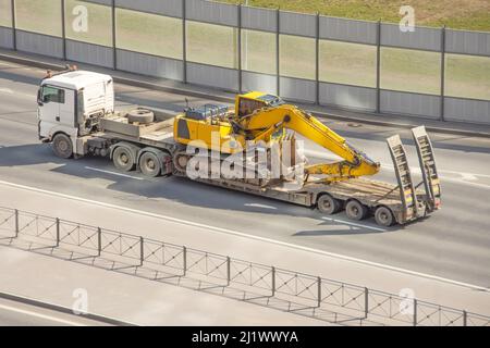 Escavatore caricato su un rimorchio per attrezzature pesanti. Autocarro per trasporto pesante. Foto Stock