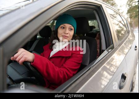 Fidata affascinante donna europea di mezza età alla guida di un'auto. Affascinante donna di successo si siede nel sedile del conducente di un'auto e guida con sicurezza su un Foto Stock
