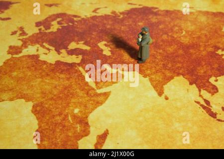 Personaggi in miniatura personaggio giocattolo fotografia concettuale. Servizio di distribuzione di notizie globale Un ufficiale di posta militare che tiene la busta del pacchetto di notizie in piedi sopra l'orecchio Foto Stock