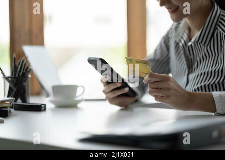 Primo piano le mani femminili in possesso di carta di credito e smartphone, giovane donna che paga online, utilizzando il servizio bancario, l'immissione di informazioni, shopping, ordini Foto Stock