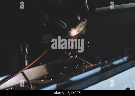 Primo piano di un produttore di metalli che effettua una saldatura automobilistica con fiamme in una fabbrica di automobili Foto Stock