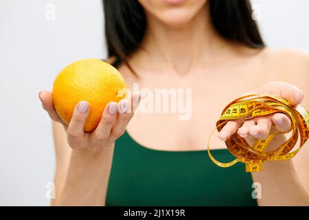 la mano della donna contiene un nastro di centimetro-lunghezza e frutta di limone. Il concetto di uno stile di vita sano, il concetto di cibo biologico naturale. Foto Stock