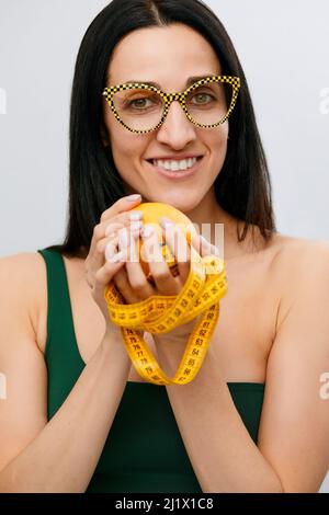 la mano della donna contiene un nastro di centimetro-lunghezza e frutta di limone. Il concetto di uno stile di vita sano, il concetto di cibo biologico naturale. Foto Stock