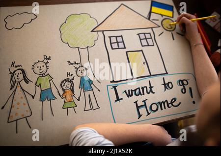 Vista dall'alto della studentessa Ucraina rifugiata che ha perso la casa e che ha disegnato la sua famiglia. Concetto di guerra ucraino. Foto Stock