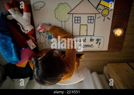 Vista dall'alto della studentessa Ucraina rifugiata che ha perso la casa e che ha disegnato la sua famiglia. Concetto di guerra ucraino. Foto Stock