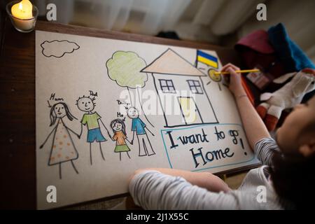 Vista dall'alto della studentessa Ucraina rifugiata che ha perso la casa e che ha disegnato la sua famiglia. Concetto di guerra ucraino. Foto Stock