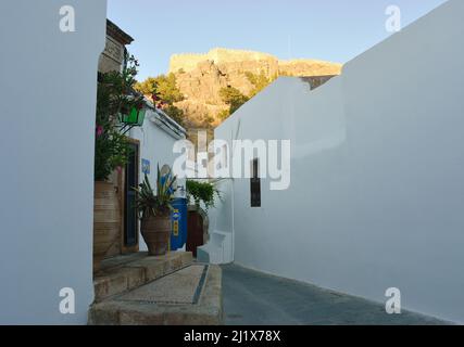 Lindos, Grecia 06-01-2021 piccola strada nel centro storico con bancomat automat con vista sull'acropoli Foto Stock
