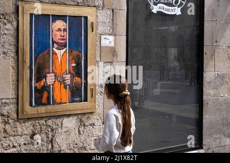 Barcellona, Spagna. 28th Mar 2022. Una donna guarda un ritratto di Vladimir Putin dietro i bar. Vladimir Putin Behind Bars è rappresentato nel nuovo collage grafico pubblico in Plaza de Sant Jaume dall'artista italiano TvBoy, con sede a Barcellona. Credit: SOPA Images Limited/Alamy Live News Foto Stock