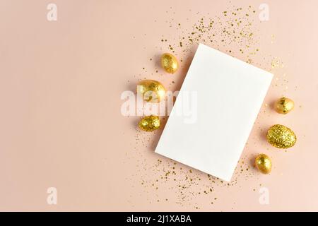 Striscione pasquale con un foglio bianco di carta e uova dorate con paillettes Foto Stock