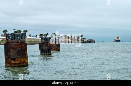 Paraurti imbottiti al molo del porto dei traghetti di Port Aransas, Texas, con acqua calma e una nave in lontananza vela sul canale di navigazione tra Golfo o Foto Stock