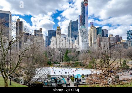 Trumps Wollman Rink con People Ice Skating durante il giorno in inverno, vista dalla distanza, Skyline di Manhattan in background, Central Park New Foto Stock