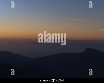 Splendida vista sulle montagne occidentali di Gran Canaria, Isole Canarie, Spagna dopo il tramonto con le sagome dell'isola di Tenerife e del Monte Teide. Foto Stock