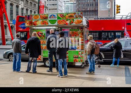 Persone in attesa in fila di fronte al camion Halal Street Food Shafiq in piedi su un marciapiede nella vista posteriore Manhattan, New York City, durante l'inverno, Horiz Foto Stock