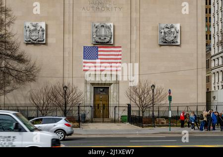 New York City Triborough Bridge e Tunnel Authority Building con ingresso dell'edificio e bandiera americana sulla parte superiore, strada con traffico e a piedi p Foto Stock