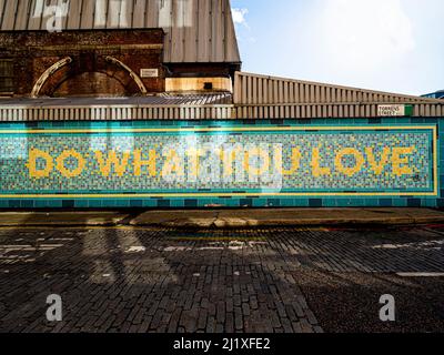 Sulla facciata della stazione originale della metropolitana Angel viene visualizzato il messaggio "Do what you love". Via Torrens. Londra. REGNO UNITO Foto Stock