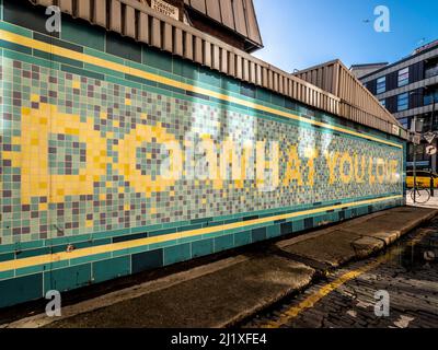 Sulla facciata della stazione originale della metropolitana Angel viene visualizzato il messaggio "Do what you love". Via Torrens. Londra. REGNO UNITO Foto Stock