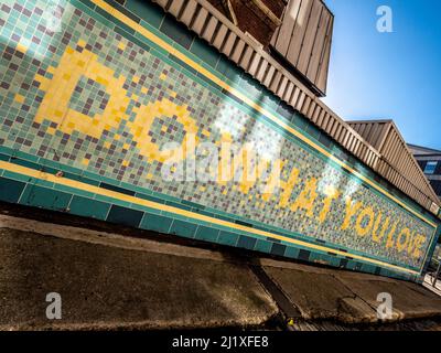 Sulla facciata della stazione originale della metropolitana Angel viene visualizzato il messaggio "Do what you love". Via Torrens. Londra. REGNO UNITO Foto Stock