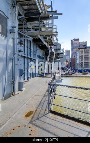 Intrepid Sea-Air-Space Museum, lato sinistro della nave con recinzione e scala, City in background, New York City durante la soleggiata giornata invernale, verticale Foto Stock