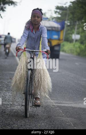 23 settembre 2020, Barisal Airport, Barisal, Bangladesh. Un bambino porta fiori di anacardi su una bicicletta Foto Stock