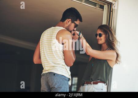 HES un romantico senza speranza. Scatto corto di una giovane coppia affettuosa che condivide un momento intimo fuori sul loro balcone. Foto Stock