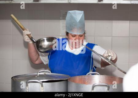 Una cuoca donna in una cucina industriale con un mestolo grande tra le  pentole in metallo. Chef all'ospedale Foto stock - Alamy