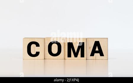 il coma di parola fatto da lettere di legno grigie giace su uno sfondo verde. Foto Stock